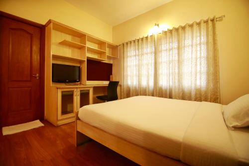 a bedroom with a bed and a desk with a television at Falcon Suites Residency Road in Bangalore