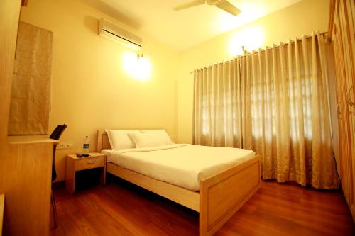Schlafzimmer mit einem Bett mit weißer Bettwäsche und einem Fenster in der Unterkunft Falcon Suites Residency Road in Bangalore