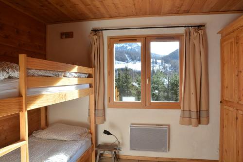 um quarto com um beliche e uma janela em joli appartement rez de jardin plein sud em Montgenèvre