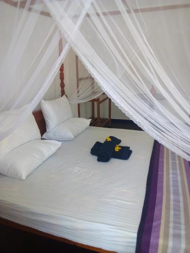 a bed with white sheets and white pillows at Daasa Guest Mirissa in Mirissa