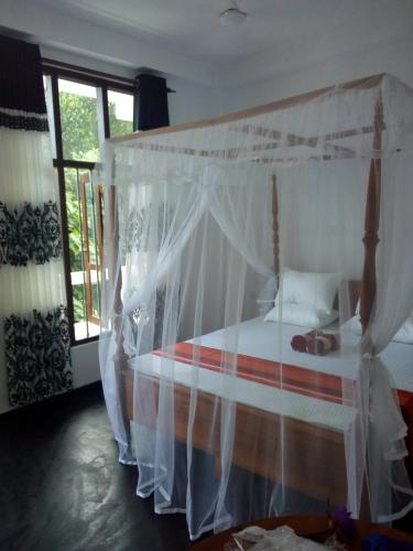 a bedroom with a canopy bed with white curtains at Daasa Guest Mirissa in Mirissa