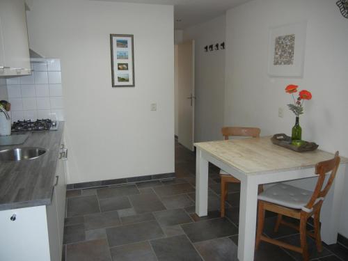 cocina con mesa, sillas y fregadero en Mooi zo 2, en De Koog