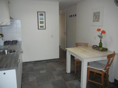 Una cocina con una mesa y sillas y un fregadero. en Mooi zo 2, en De Koog