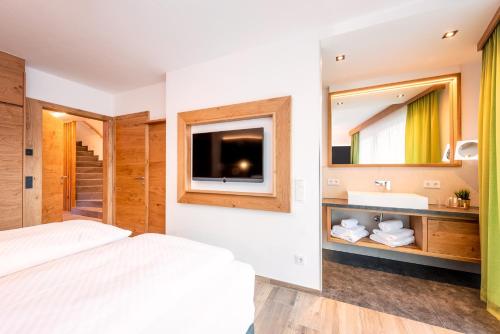 a bedroom with a bed and a sink and a mirror at Gasteg Living in Maria Alm am Steinernen Meer