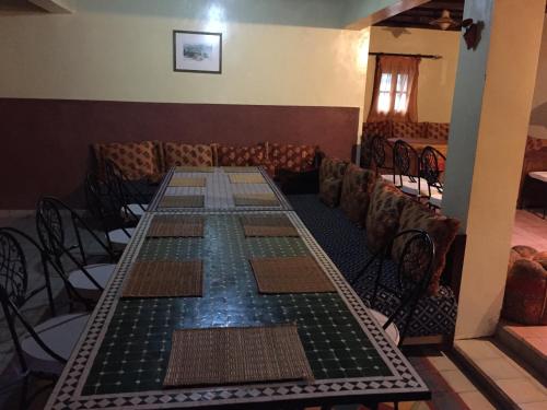 uma mesa longa numa sala com cadeiras e um estofados de esteira de mesa em Safranière du M' Goun em Aguerd nʼOuzrou
