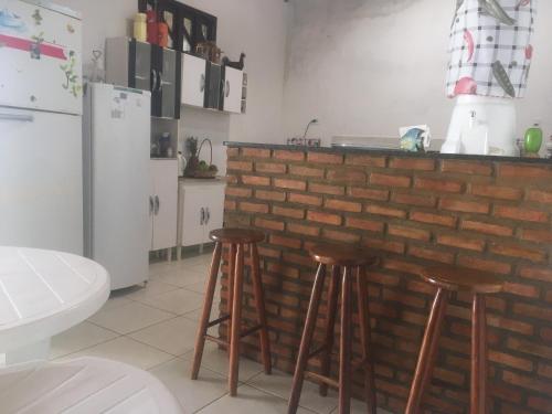 a kitchen with a counter with stools and a refrigerator at Casa Praia Lagoa dos Tambaquis - Abaís in Estância