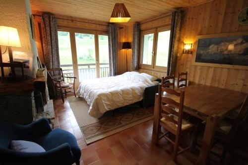 een slaapkamer met een bed en een tafel en stoelen bij Orée des pistes in Combloux