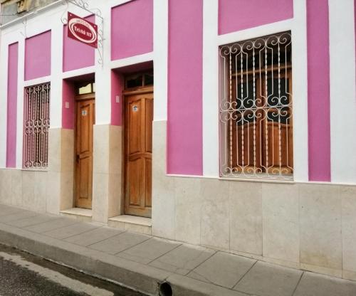 a pink and white building with wooden doors at Hostal Trista 117 in Santa Clara