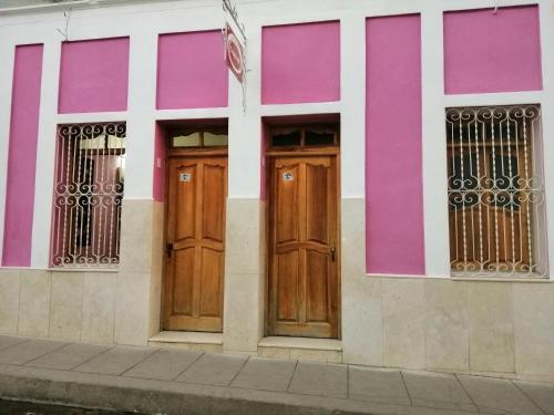 a building with two wooden doors and pink at Hostal Trista 117 in Santa Clara