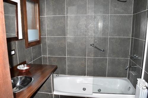 y baño con bañera y lavamanos. en Andyna - Cabaña frente al río en Trevelín