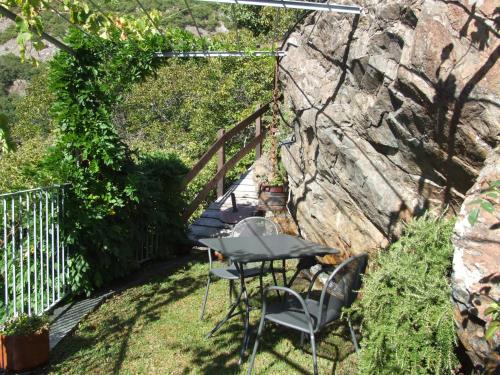 a patio with a table and chairs next to a stone wall at Le Rocher in Châtillon