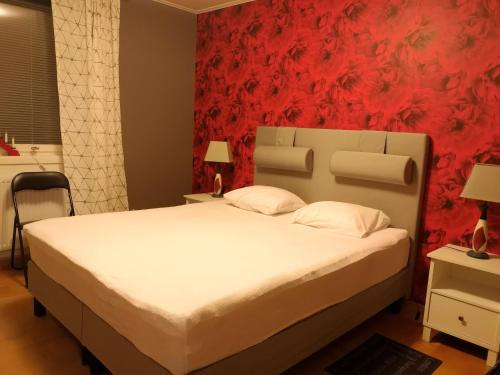 a bedroom with a white bed with a red wall at Holiday Home Byvägen 38 in Nattavaara