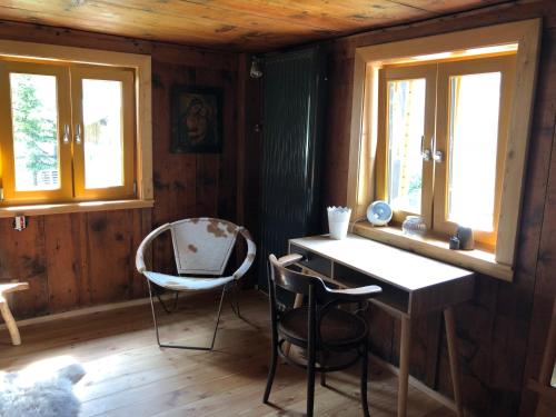a room with a desk and two chairs and windows at Klösterle 72 -Annas Lodge in Klösterle am Arlberg