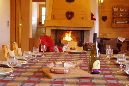 a table with glasses and a bottle of wine and a fireplace at Chalet Le Sabot De Venus in Combloux