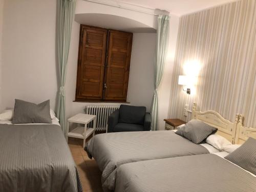 a hotel room with two beds and a chair at MONASTERIO de SANTA MARÍA DE VALVANERA in Anguiano