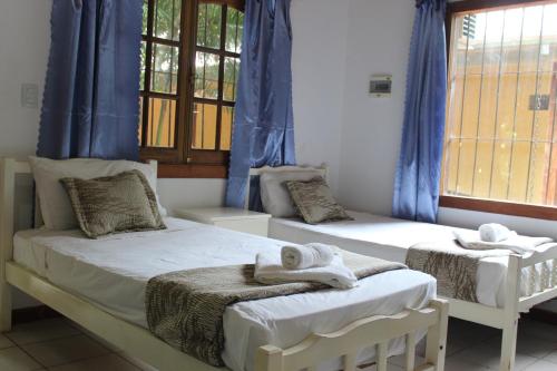 two beds in a room with blue curtains and towels at Palo Rosa Lodge in Puerto Iguazú