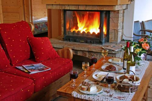 a living room with a fireplace and a table with wine glasses at Chalet Le Sabot De Venus in Combloux
