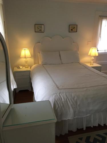 a bedroom with a large white bed with two lamps at House on Chase Creek in Shelter Island Heights