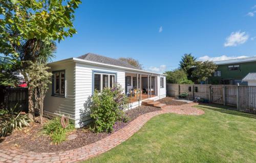 a small white house with a yard at Morning Bloom Cottage Bed and Breakfast in Nelson