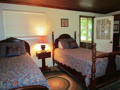 1 Schlafzimmer mit 2 Betten, einer Lampe und einem Fenster in der Unterkunft The Yearling Cabins in Cross Creek