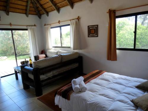 a bedroom with a bed and a couch and windows at Aloha Village in La Pedrera