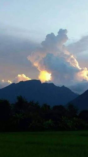 a sunset over a field with mountains in the background at Ban Thung Talay Mok Chiangdao in Chiang Dao