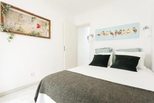 リスボンにあるThe Garden - Charming 1 Bedroom Apartment in Graçaの白いベッドルーム(ベッド1台付)が備わります。壁に絵が描かれています。