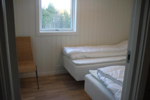 a room with two beds and a window and a chair at Bjørndalsvatnet in Hornnes