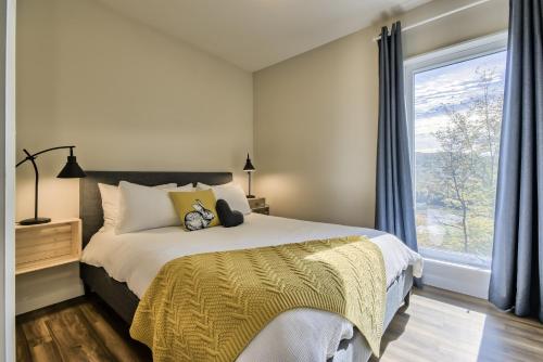 a bedroom with a bed and a large window at Modern Chalet with Mountain and Lake view by Reserver.ca in Sainte-Adèle