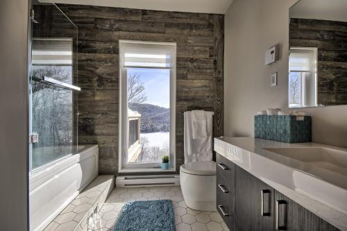 een badkamer met een wastafel, een toilet en een raam bij Modern Chalet with Mountain and Lake view by Reserver.ca in Sainte-Adèle