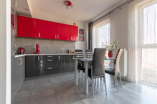 ワルシャワにあるApartament Metropolia typu deluxeのキッチン(赤いキャビネット、テーブル、椅子付)
