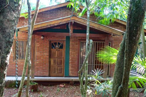 a small brick house with a wooden door in a forest at Palo Rosa Lodge in Puerto Iguazú