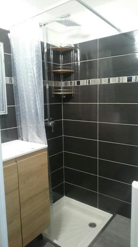 La salle de bains est pourvue d'une douche et d'un mur en carrelage noir. dans l'établissement Le Montana, à Les Deux Alpes
