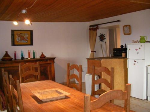 une cuisine avec une table en bois et un réfrigérateur dans l'établissement Grand Gîte à la ferme, à Les Costes-Gozon