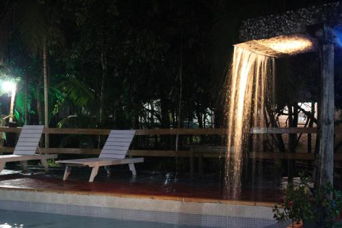 a fountain with two white benches next to a pool at Palo Rosa Lodge in Puerto Iguazú