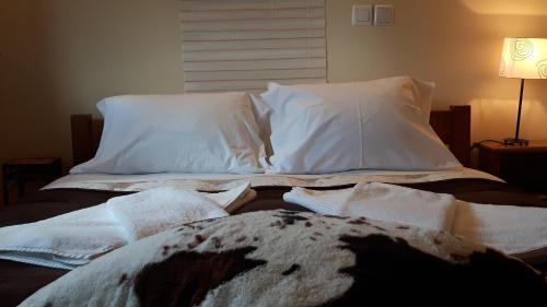a bed with white sheets and pillows on it at Maison Christiana's in Kalavrita