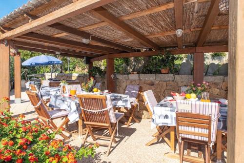 een terras met tafels en stoelen onder een houten pergola bij Résidence Villa Smeralda in Telti