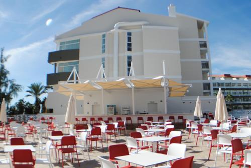 a group of tables and chairs with umbrellas in front of a building at Gara Suites Golf & Spa in Playa de las Americas