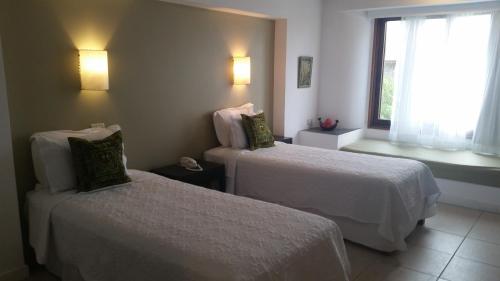 a hotel room with two beds and a window at Posada de los Pajaros in Punta del Este