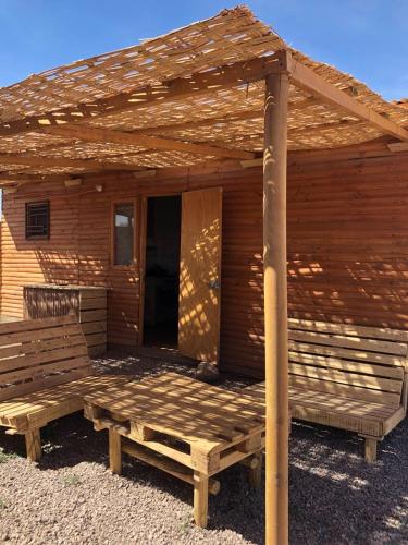 a wooden cabin with a porch and a bench at Cabaña Laynaturi in San Pedro de Atacama