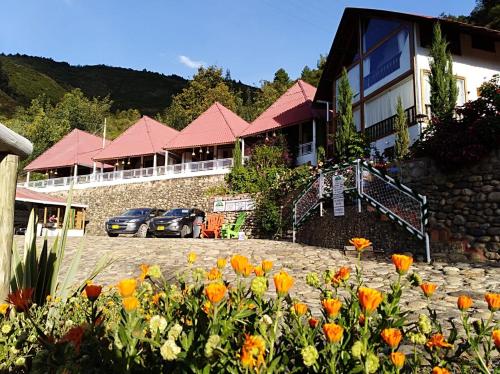 a building with a bunch of flowers in front of it at Hotel Cabañas El Rincón de las Campanas in Nobsa
