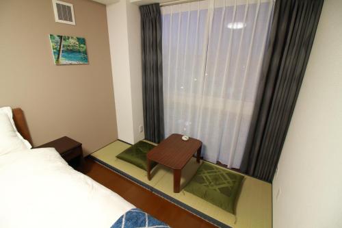 a room with a bed and a table next to a window at W&M House in Kanazawa