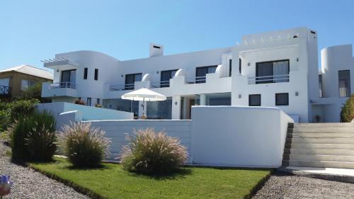 een wit huis met een hek en wat planten bij Posada de los Pajaros in Punta del Este