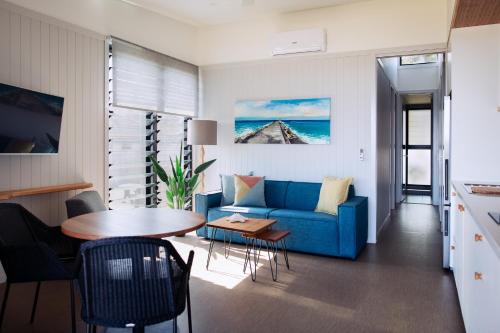 a living room with a blue couch and a table at Reflections Shaws Bay - Holiday Park in Ballina