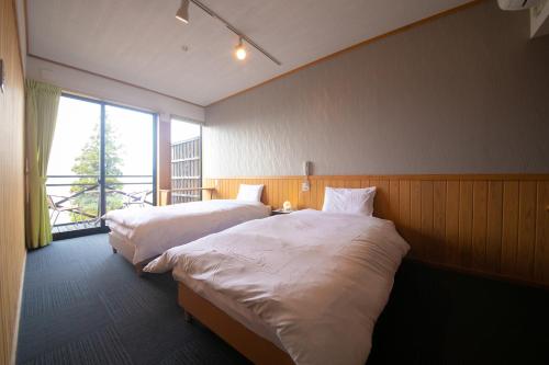 a hotel room with two beds and a window at Ryokan Yufusan in Yufuin
