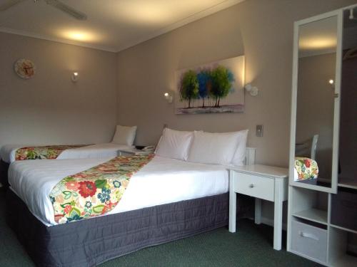 a hotel room with two beds and a mirror at Colonial Lodge Motel in Taupo