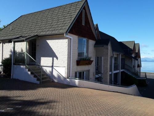 a house with a staircase next to the ocean at Colonial Lodge Motel in Taupo