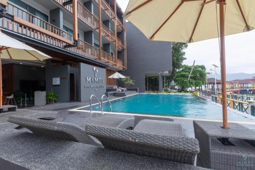 un hotel con piscina con sillas y sombrilla en Mimpi Perhentian en Perhentian Island