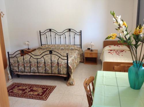 a bedroom with two beds and a table with a vase of flowers at La Pineta Residence in Otranto