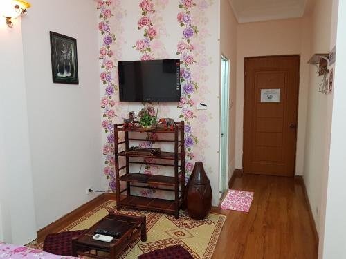 a living room with a television on a wall with flowers at Hanu's House in Hanoi